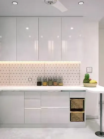 A stunning modular kitchen transformation. This all-white kitchen feels bright and spacious, featuring high-gloss cabinets, a patterned backsplash, and a clever peninsula that doubles as a breakfast counter.