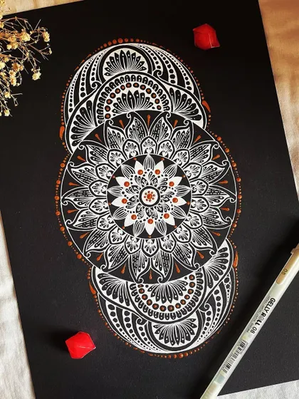 A unique, triple-circle mandala in white and bronze on black paper. This design plays with overlapping shapes and is a great example of more experimental compositions.