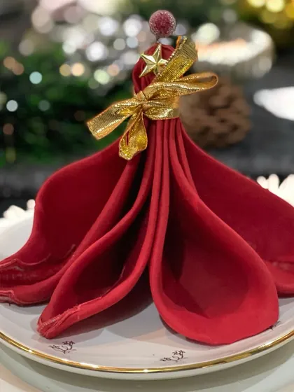 This Christmas napkin fold is designed to look like a festive tree, complete with a star on top. It's a charming and whimsical detail that adds a touch of holiday magic to each place setting.