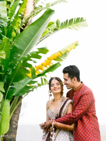An intimate portrait of the couple nestled amongst giant banana leaves, a creative and natural framing that highlights their closeness.