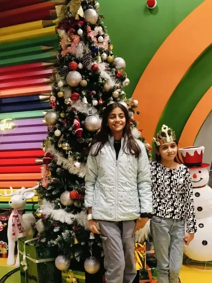 Two sisters pose in front of the Christmas tree and snowman, enjoying the holiday spirit at Tingaland.