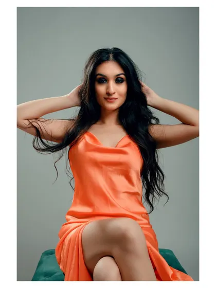 A glamorous portrait in a vibrant orange dress. The model's pose is confident and elegant, creating a striking image.