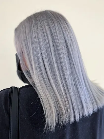 A stunning global ash gray hair color. This look is sleek, modern, and makes a bold statement with its solid, cool-toned silver shade.