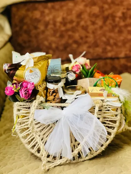 A beautiful wedding gift hamper in a rustic jute bag. It's filled with Ferrero Rocher chocolates, premium nuts, and other gourmet treats, finished with a delicate white net bow.