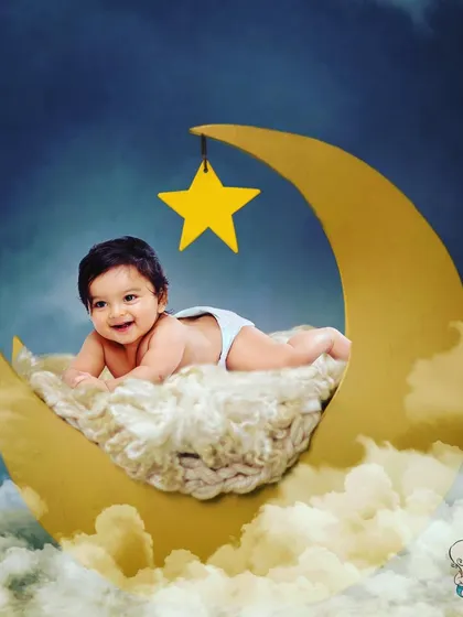 A smiling baby lying on a crescent moon prop, surrounded by clouds and a starry night sky. This dreamy and peaceful setup is perfect for capturing a magical infant portrait.