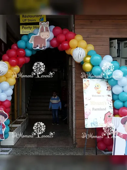A colorful balloon arch with a horse cutout and farmer props creates a fun and welcoming entrance to the farmland party.