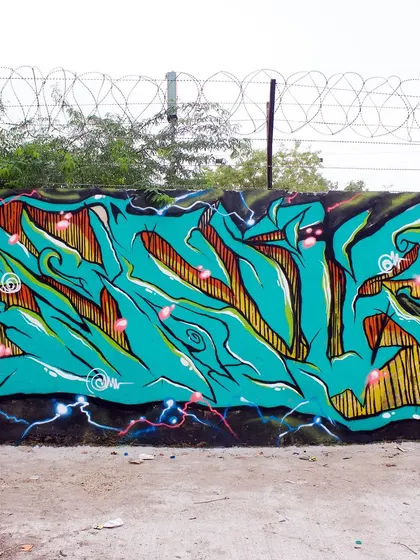A vibrant turquoise wildstyle piece from a Delhi graffiti jam. The piece is full of energy, with electric sparks and sharp, flowing letters.