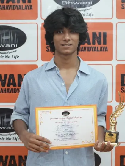 A young man proudly holds his certificate and trophy.