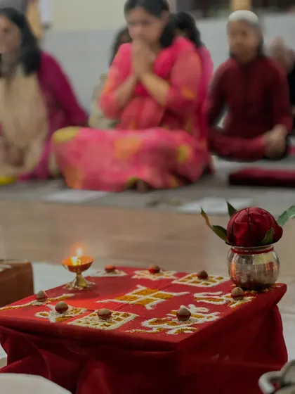 In the foreground, a sacred altar is prepared for a puja, while participants sit in meditation behind it. This image shows the integration of ritual and meditation in our practice.