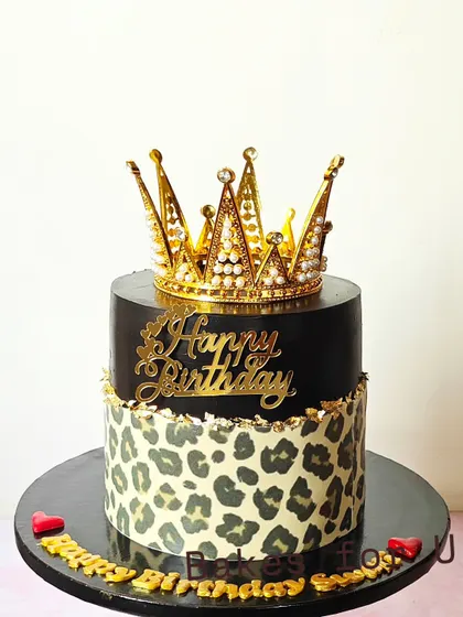 A fierce and fabulous birthday cake with a leopard print bottom tier and a sleek black top tier, crowned with a golden tiara.