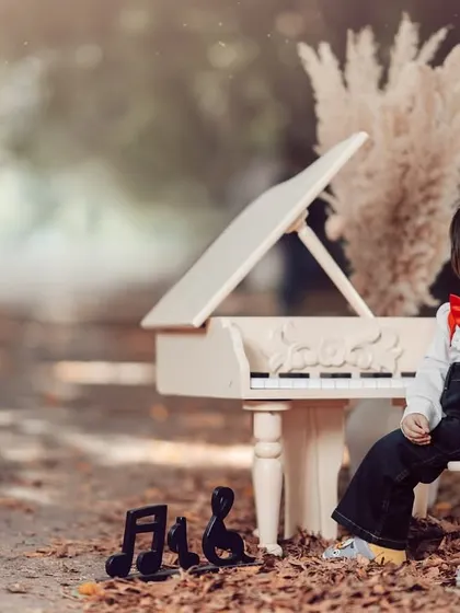 A sweet smile from a little artist. Surrounded by vintage props and his miniature piano, this little boy's portrait is full of charm and character.