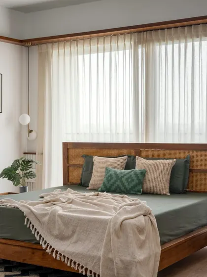 The master bed in 'Vasudhalayah' features a beautiful cane headboard and is dressed in earthy green linens. The space is a perfect fusion of classical details and contemporary comfort.