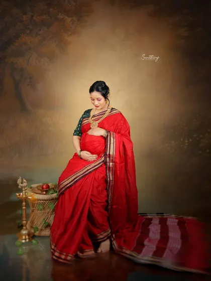 A quiet moment of anticipation captured in a beautiful red saree. The traditional props and painterly backdrop create a rich, artistic portrait that feels both personal and timeless.