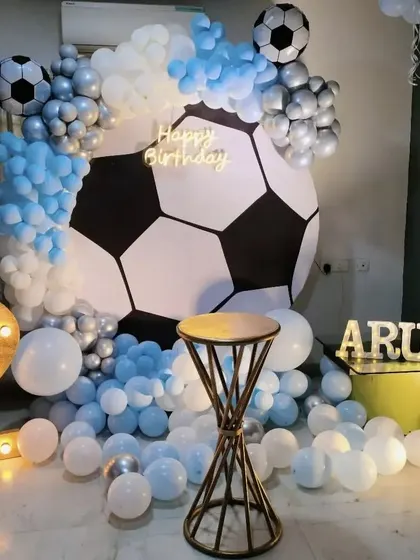 A goal-worthy celebration for a football fan. This soccer-themed decor features a giant football backdrop, light-up numbers, and a balloon arrangement in team colors.