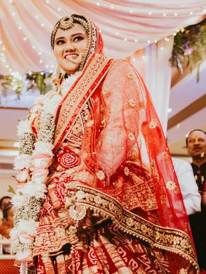 A candid shot of the bride during her Varmala ceremony. Her upward glance and smile capture a moment of pure happiness and excitement.