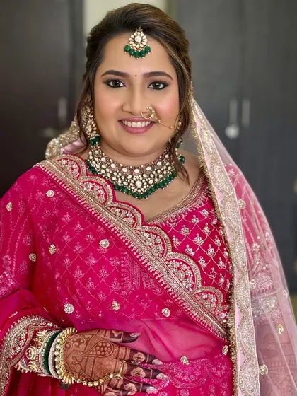 A full view of the bride's stunning pink lehenga and the beautiful details of her look. The makeup is balanced to feel both traditional and fresh.