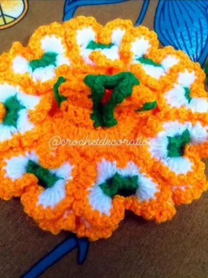 A classic floral-patterned crochet poshak for a size 2 Kanha ji. This dress combines bright orange, white, and green wool in a traditional circular design, complete with a small matching pagdi.