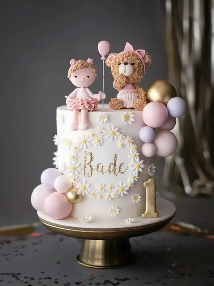 A sweet and whimsical cake for a first birthday. This design features a cute doll, a teddy bear, and daisy details in soft pastel colors.