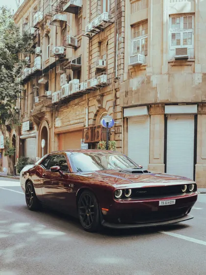 A powerful Dodge Challenger muscle car on a quiet street in Mumbai. The warm lighting and classic architecture in the background make the car stand out even more.