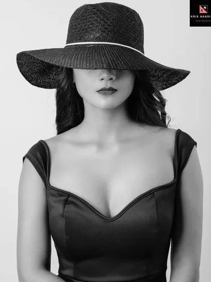 A dramatic black and white portrait where the model's face is completely hidden by a large hat. This shot is all about creating mystery, focusing on the silhouette and the form of the dress.