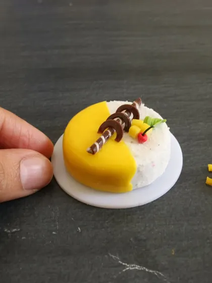 A close-up of the mango cake being decorated with tiny chocolate swirls.