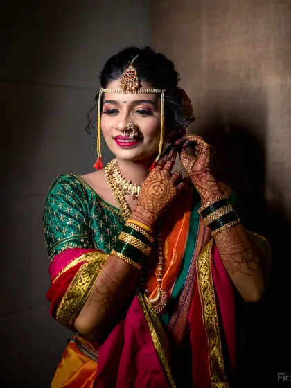 A joyful bridal portrait capturing a candid smile as she adjusts her traditional jewelry.