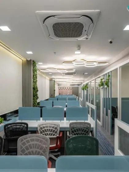 An overview of the open-plan workstation area we designed. The layout uses low partitions to foster collaboration while maintaining personal space, with biophilic elements and hexagonal ceiling lights adding a touch of modern design and well-being.