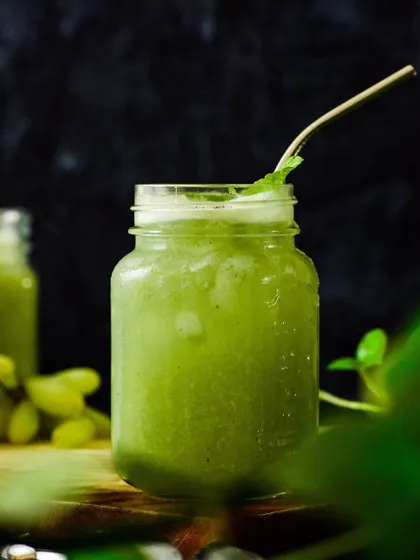 A green grape slushy in a mason jar against a dark background. The lighting from the side highlights the icy texture and makes the drink look incredibly cool and refreshing.