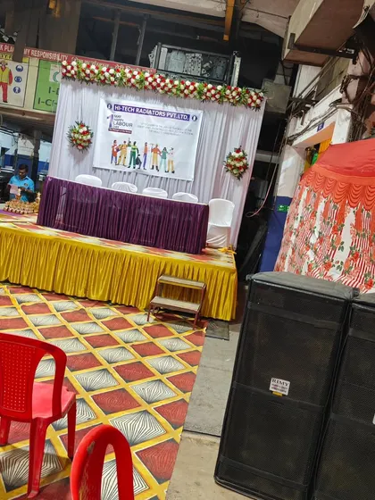 Another angle of the Labour Day event setup, showing the stage, speakers, and seating area.