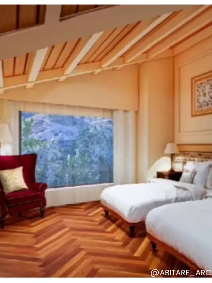 A twin bedroom design for the Nahan hotel. This room features warm wooden floors in a herringbone pattern, a large picture window, and classic furniture, including a high-backed wing chair for a cozy reading corner.