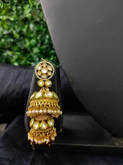 A close-up of a double jhumka earring with kundan work and pearl drops. This rental piece offers a grand and traditional look.