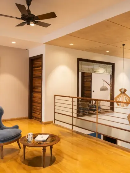 The spacious lounge on the first floor of Ashraya Residence serves as a communal gathering space. Its elegant wooden flooring and minimal decor draw inspiration from the adjacent double-height courtyard.