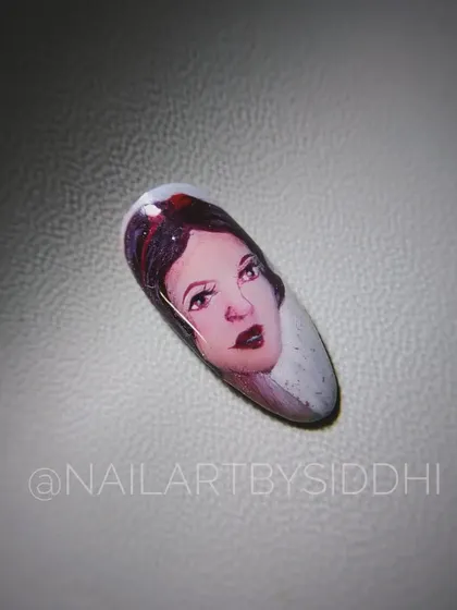A close-up of a single press-on nail with a hand-painted portrait of Disney's Snow White. I focused on capturing her classic, gentle expression.