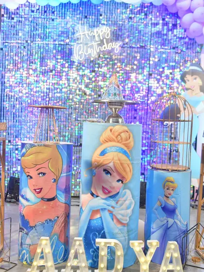A detailed shot of the princess-themed cake tables, featuring Cinderella and a 'Happy Birthday' neon sign against the sequin wall.