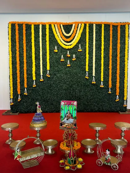 A full view of a greenery wall backdrop set up for a ceremony. The stage is prepared with small offering tables and props, ready for the main event.