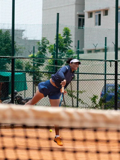 A female athlete practicing her serve on the clay court. We focus on developing a powerful and reliable serve for all our players.