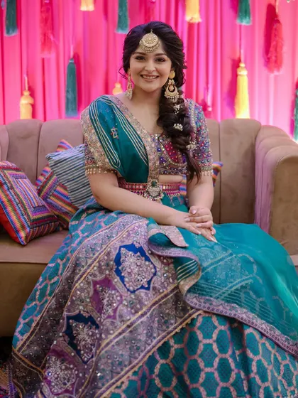 The full view of the bride in her stunning multi-colored lehenga, with her hair styled in a romantic side braid.