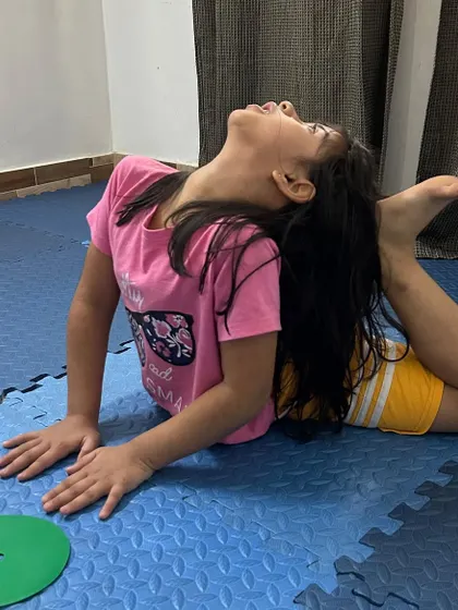 This young dancer is mastering the one-legged king pigeon pose, a deep stretch that improves flexibility in the hips and spine.