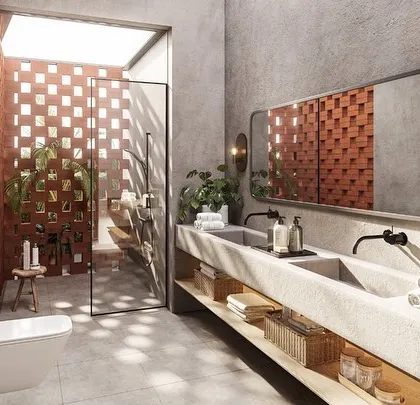 The master bathroom in a Kolgaon villa features a long concrete vanity and an open-air shower. The shower is enclosed by a perforated brick wall, giving the feeling of bathing outdoors while maintaining complete privacy.