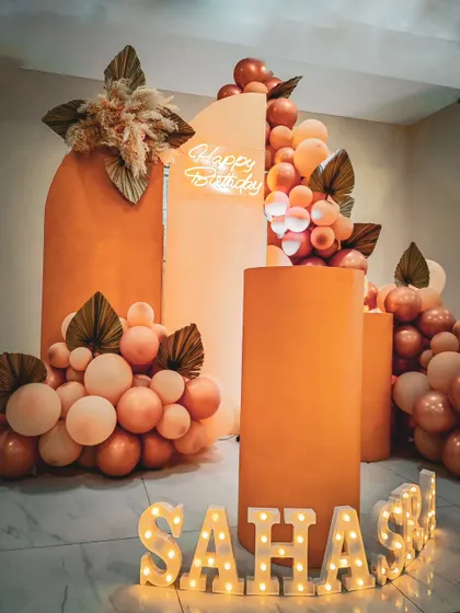 A boho-inspired birthday theme in warm terracotta tones. The arched backdrops, balloon garlands, and dried palm leaves create a trendy and aesthetic look.