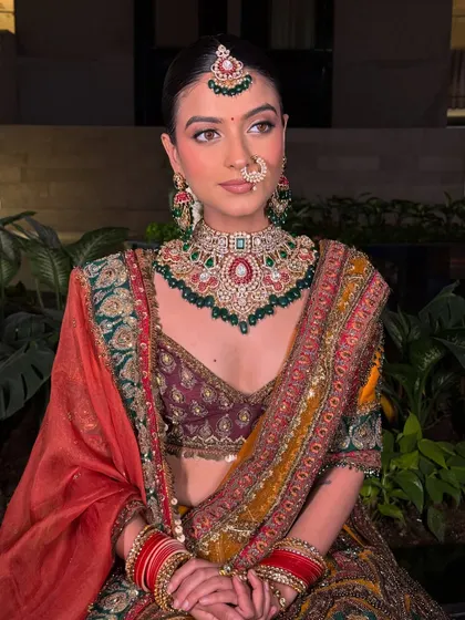 A full view of a bride adorned in our heritage jewellery. The intricate choker, matching earrings, and maang tikka create a regal look against her multi-colored lehenga.