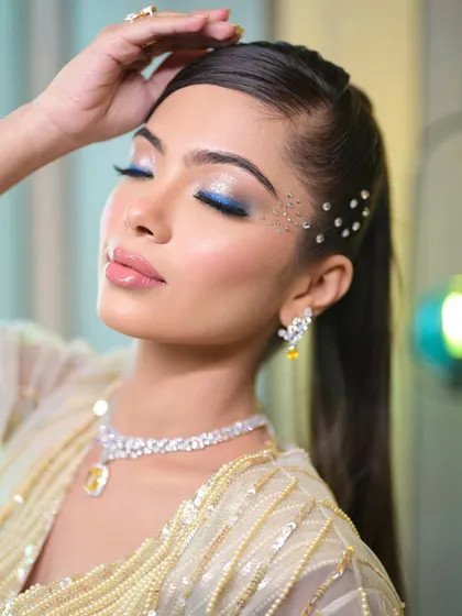 A super glam cocktail look with a pop of blue liner and scattered face crystals. This is a perfect example of combining classic glam with creative, modern elements.