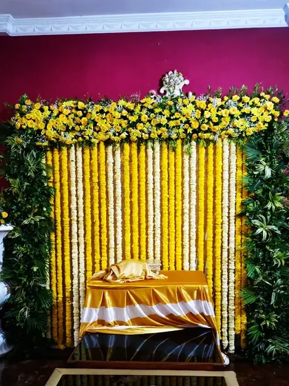 An elegant marigold floral backdrop created for a Varamahalakshmi pooja. The traditional yellow and white flower strings create a divine and festive atmosphere for worship.