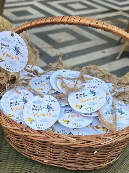 A basket of custom "Thank you for flying by" tags, ready to be attached to first birthday party favors.