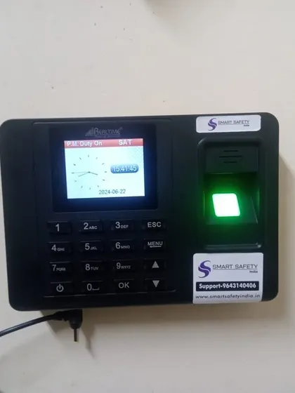 A newly installed Realtime biometric attendance system, ready for use. The clear screen displays the time and date, and the green light on the scanner indicates it's active.
