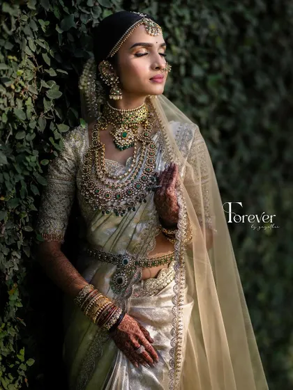 A moment of peace and beauty. The bride's eyes are closed, showing off the soft, shimmery eyeshadow that complements her elegant white and gold saree.