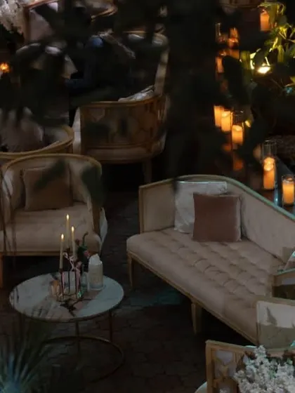 The outdoor lounge area for a reception, illuminated by fairy lights and candles. The elegant white furniture and surrounding greenery created a cozy and romantic space for guests to relax.