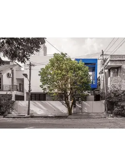 The 'Cube Square' residence, where a bold blue cube punctuates the white facade, creating a distinct architectural identity. The design preserves an existing tree, which becomes a central element that the house is built around, showcasing our context-sensitive approach.