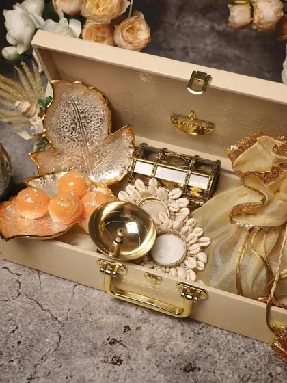 This wooden suitcase hamper is filled with traditional Diwali decor and sweets. It includes leaf-shaped platters, a treasure box, and motichoor ladoos, making it a very special festive gift.