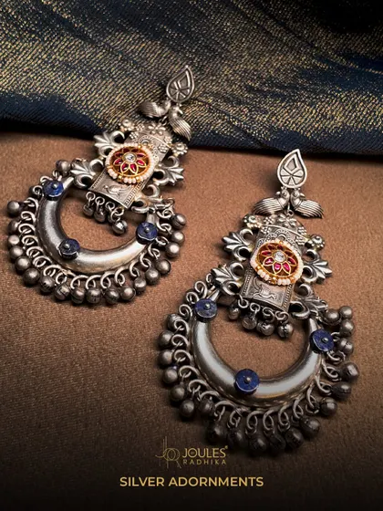 Silver adornments that tell a story. These crescent-shaped chandbalis are crafted from oxidized silver and accented with blue stones.